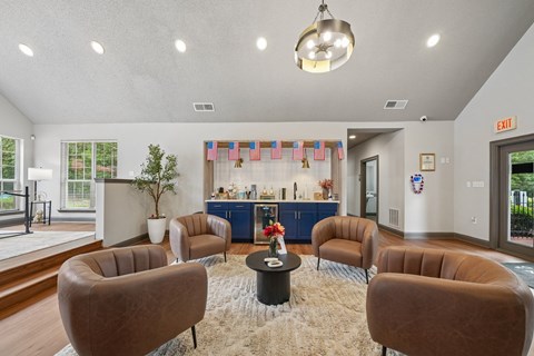 A living room with brown chairs and a round table with a vase of flowers on it.