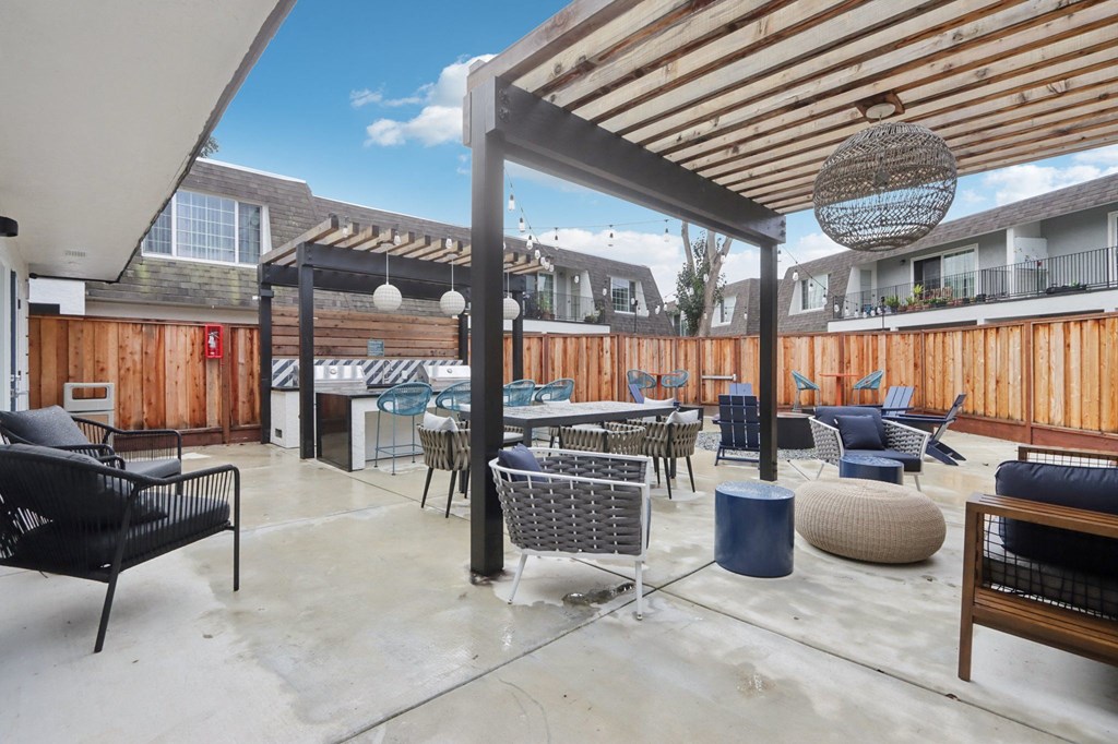 A patio with a black chair and a blue table.