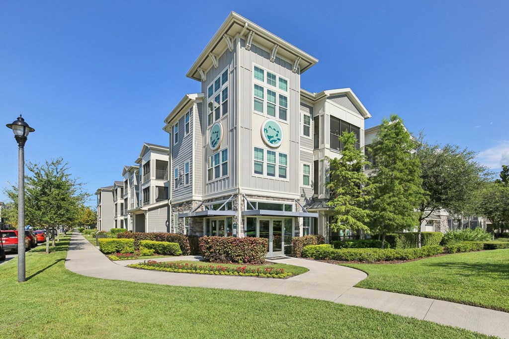 A large, modern building with a green lawn in front.