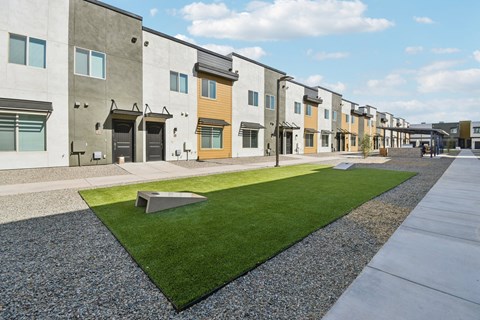 A row of modern townhouses with a grassy area in the foreground.