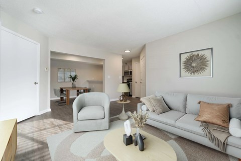 A living room with a grey couch, a white coffee table, and a grey armchair.