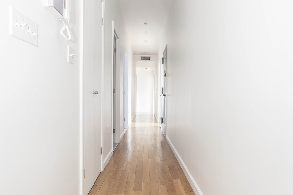 a long white hallway with white walls and wood floors