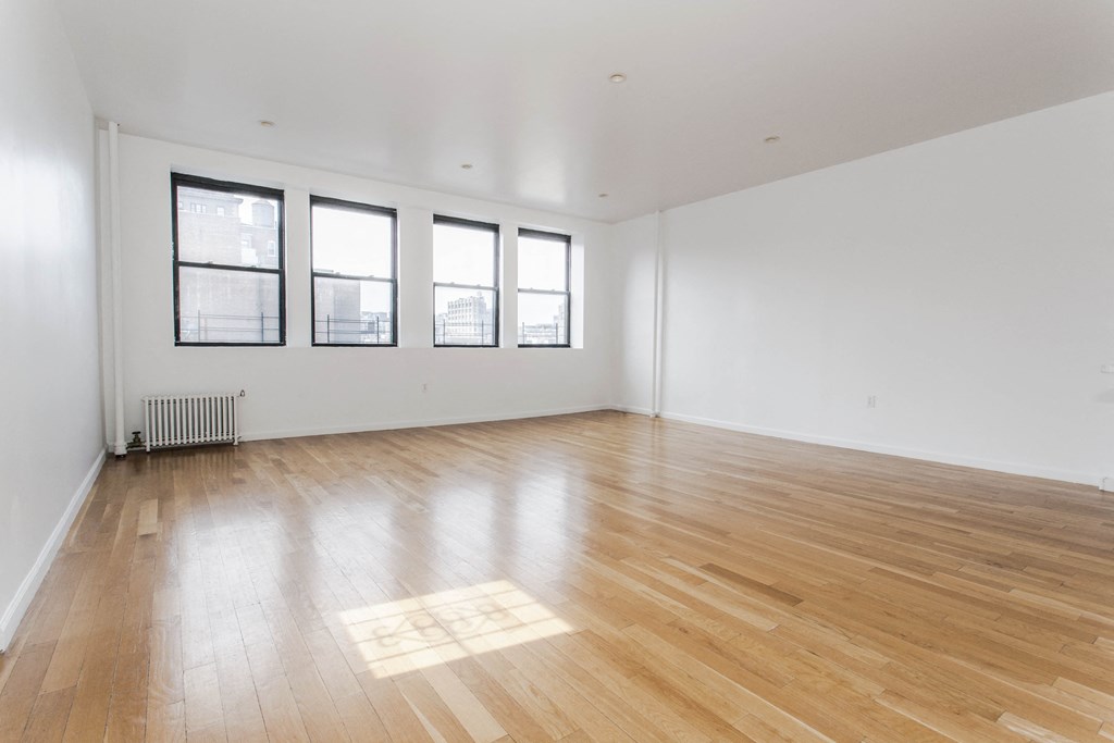 an empty living room with wood floors and windows