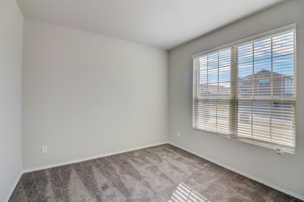an empty living room with a large window and carpeting