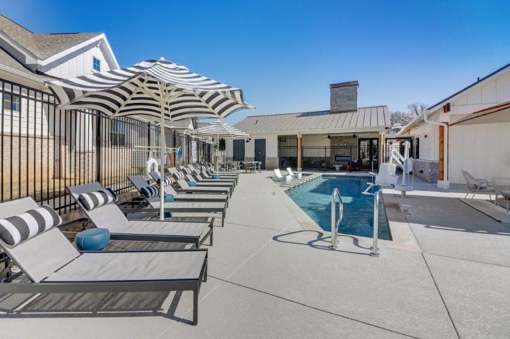 a pool with lounge chairs and umbrellas next to a building