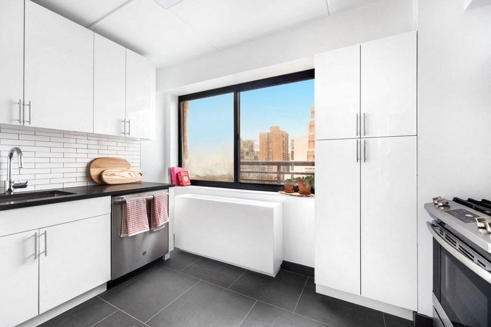 a kitchen with white cabinets and a window