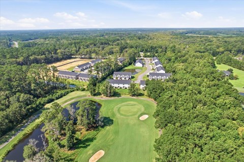 A golf course with a clubhouse and several houses in the background.