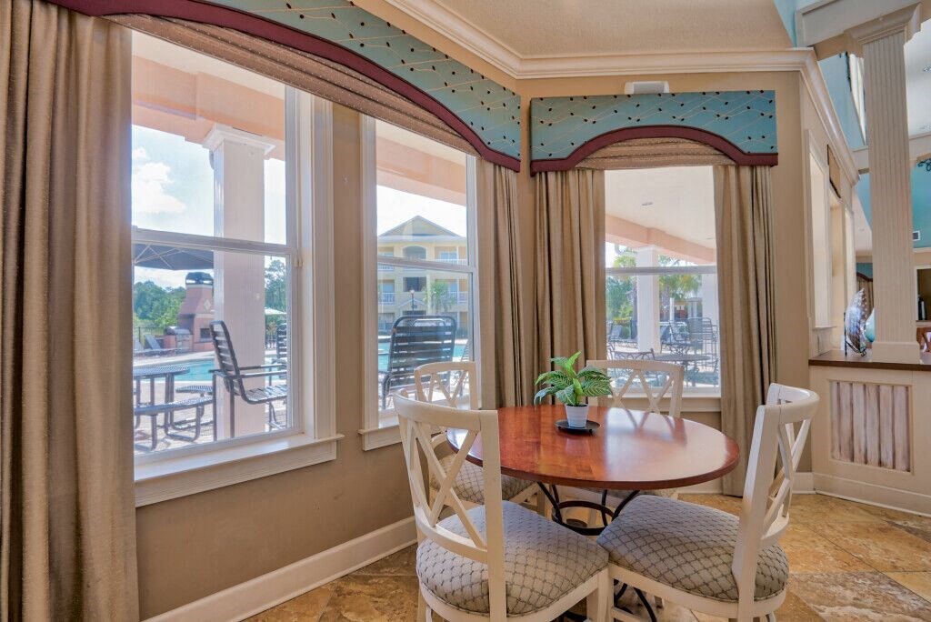 Pet-Friendly Apartments in Hinesville, GA – Tattersall Village - clubhouse seating area with table and chairs and view of the pool