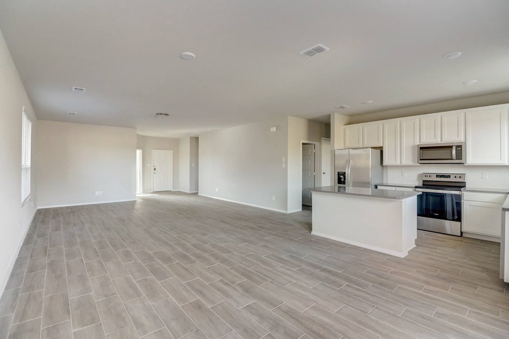 the living room and kitchen of an empty house