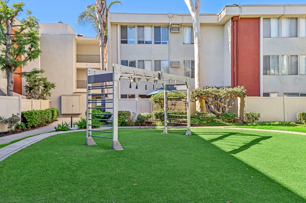 A playground with a slide and swings in front of a building.