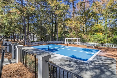 Element at 3900, Macon Apartments A blue pool surrounded by a fence and trees.