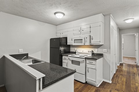 A kitchen with black appliances and white cabinets.