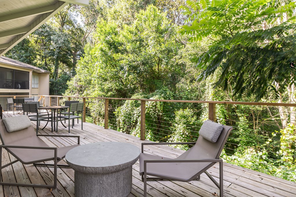 a deck with a table and chairs and trees in the background
