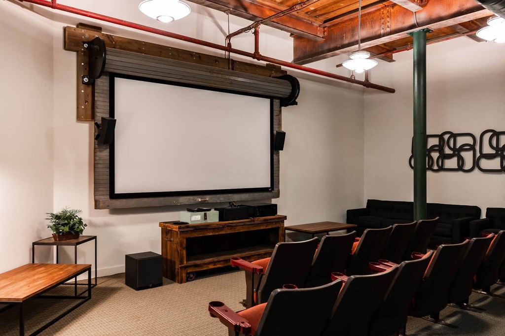 Home theater with projector screen, theater seating, and industrial-style decor.