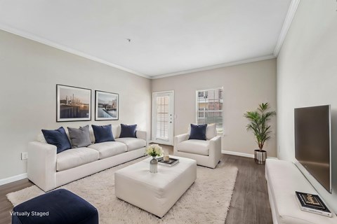 A living room with a white couch, a white chair, a white coffee table, and a white rug.