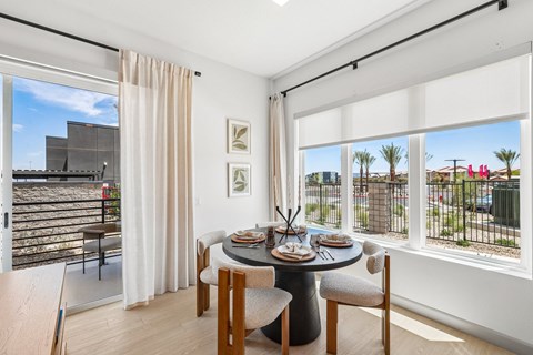 A dining room with a table set for two and a view of the outside.