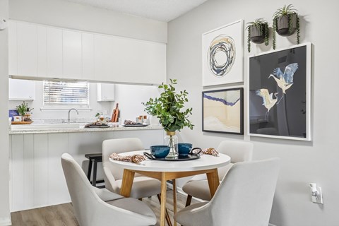 A dining room with a table set for two and a potted plant on the table.