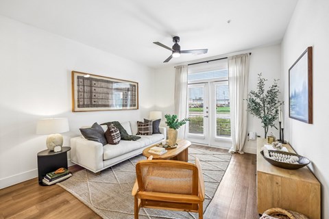 A living room with a white couch, a wooden chair, and a painting on the wall.