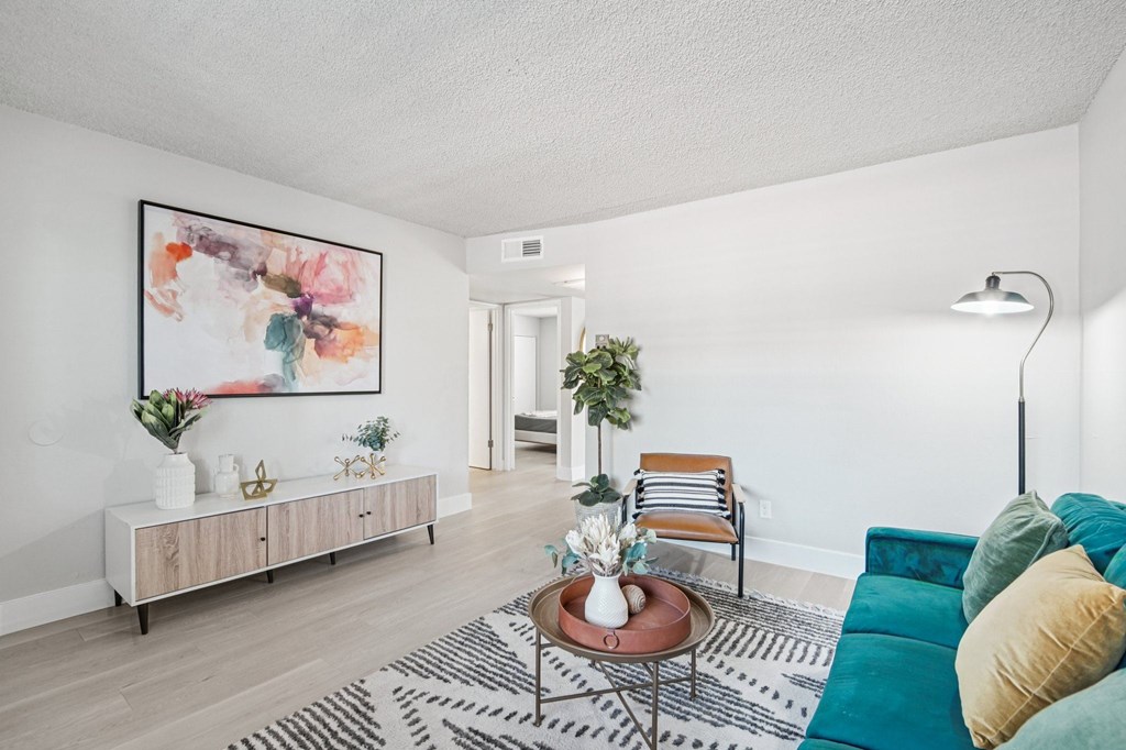 A living room with a green couch and a painting on the wall.
