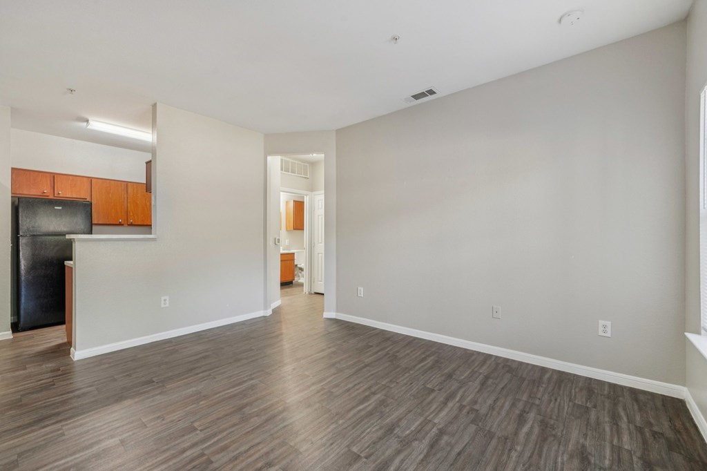 A spacious living room with wood flooring and a television.