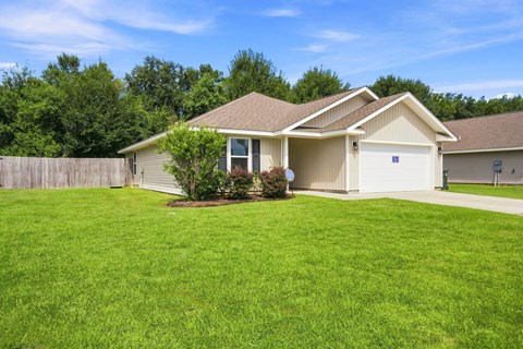 A house with a brown roof and a green lawn.