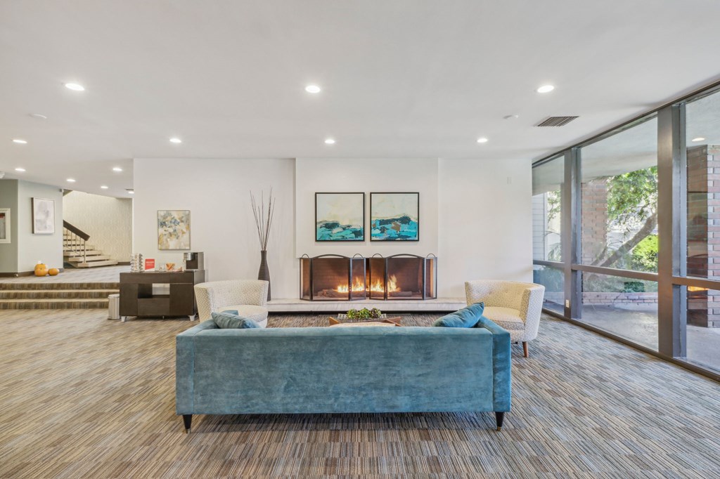 A modern living room with a fireplace and a blue couch.