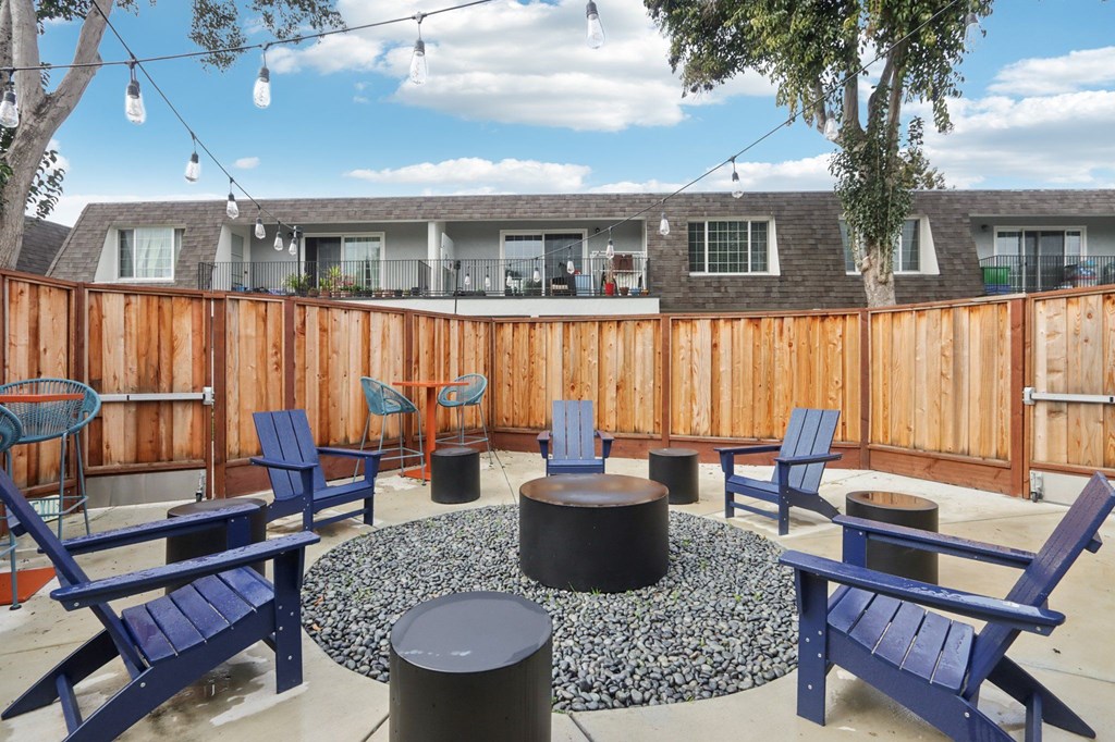 A patio with blue chairs and a fire pit.