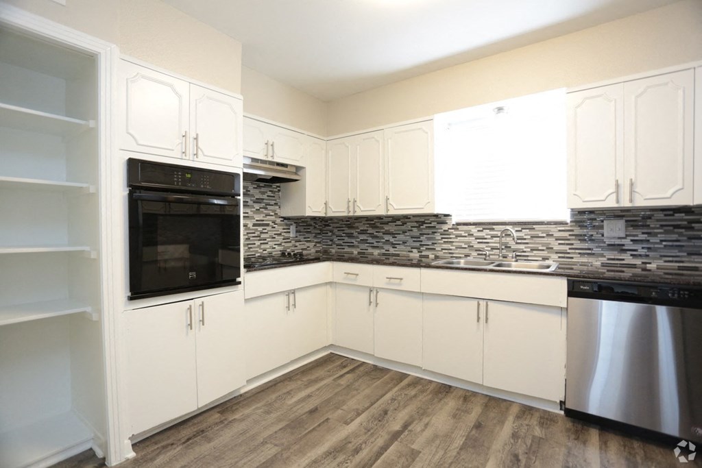 a kitchen with white cabinets and a stainless steel oven and microwave