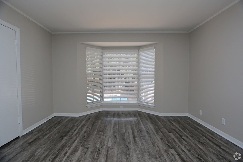 an empty living room with a large window and wood floors