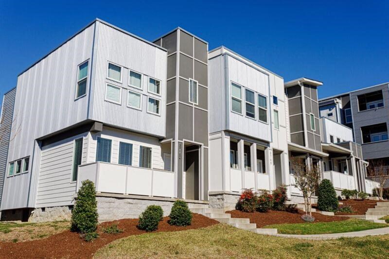 a group of white houses with grass and trees
