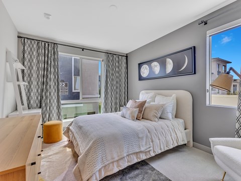A bedroom with a large bed and a window with curtains.