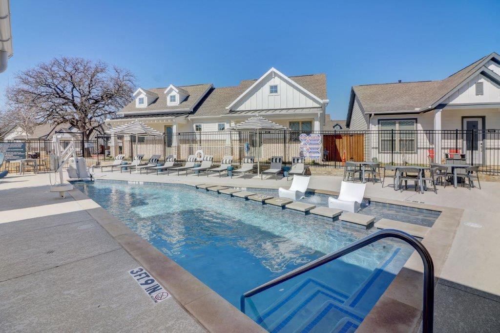 a pool with lounge chairs and houses in the background