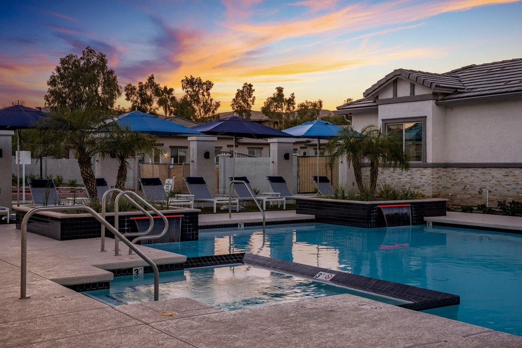 A pool surrounded by a patio and a few trees.