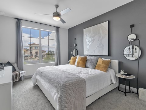 A bedroom with a large bed and a view of a building outside the window.