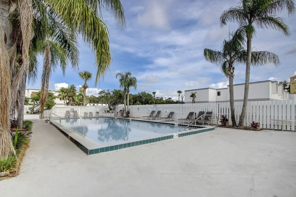 Derby Park Apartments in Daytona Beach, FL photo of the pool is surrounded by palm trees and a white fence