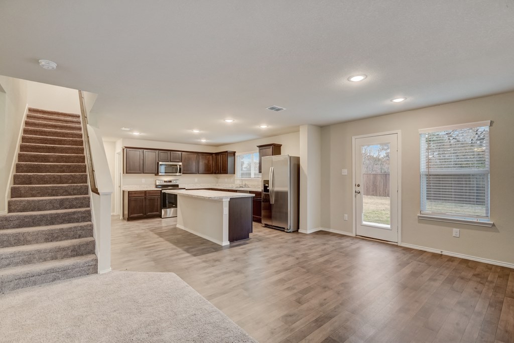 an open kitchen and living room with a staircase leading up to it