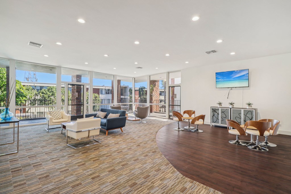 A living room with a wooden floor and a large TV mounted on the wall.