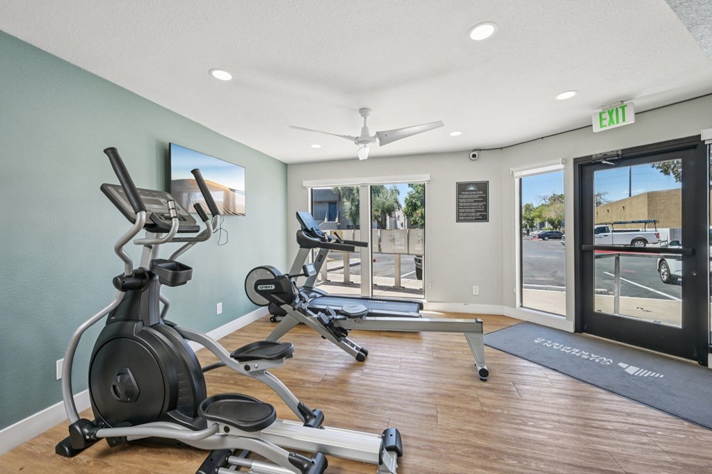 A gym with a row of exercise bikes and a treadmill.