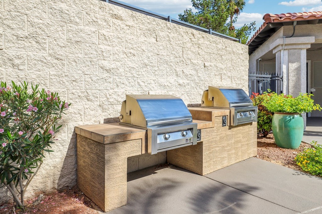 A small outdoor grill area with a stone wall and a green pot.