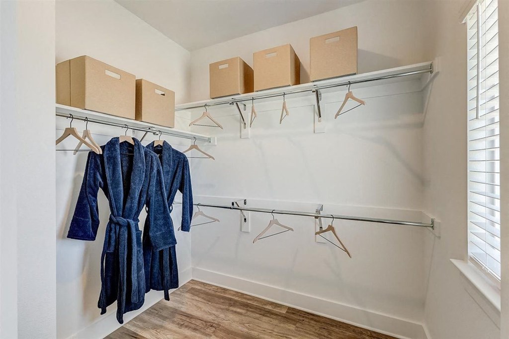 a walk in closet with white walls and a window