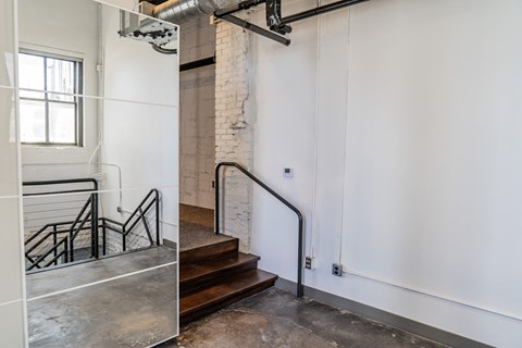 two views of a stairwell in a building with white walls and a glass door