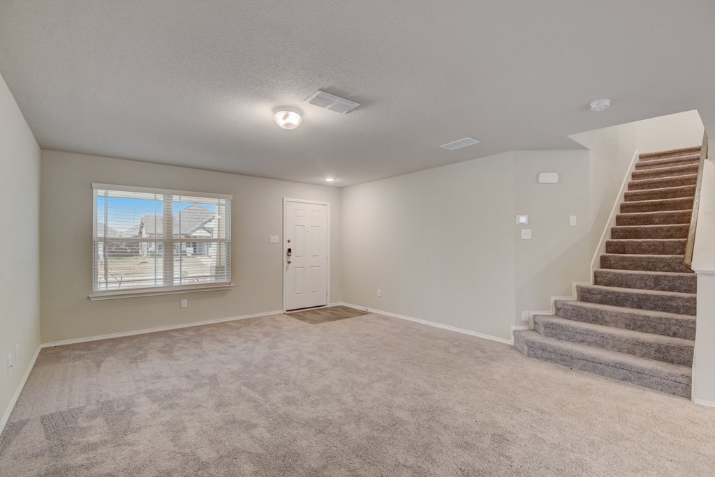 an empty living room with a staircase and a window