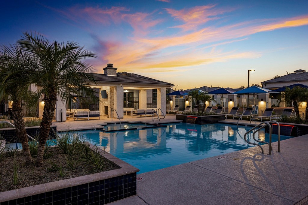 A pool surrounded by palm trees and lounge chairs.