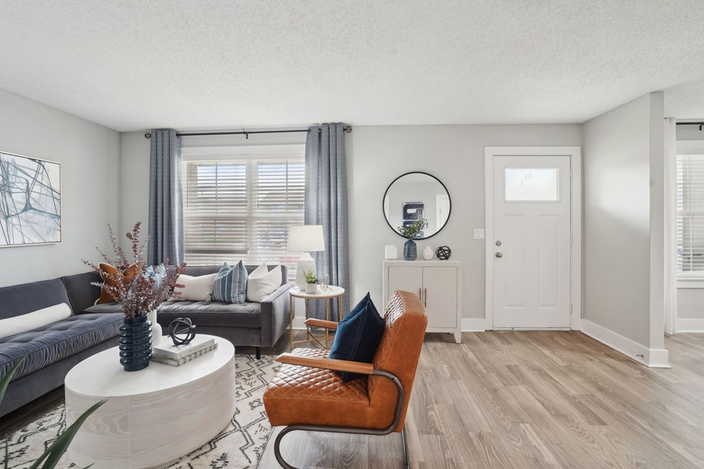 Modern living room with gray sofa, leather chair, white coffee table, and wood floors.