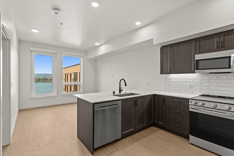 A modern kitchen with dark brown cabinets and stainless steel appliances.