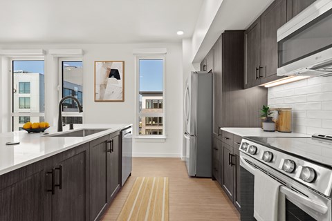 A modern kitchen with dark wood cabinets and stainless steel appliances.