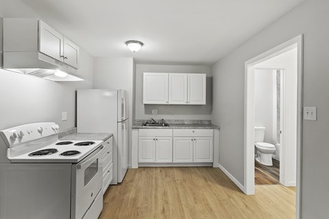 A white kitchen with a stove top oven and a refrigerator.