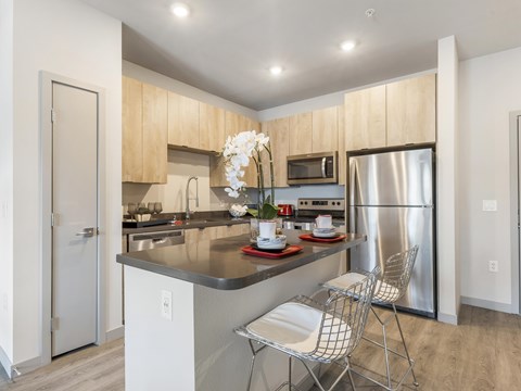 A kitchen with a refrigerator, sink, and a dining table with chairs.