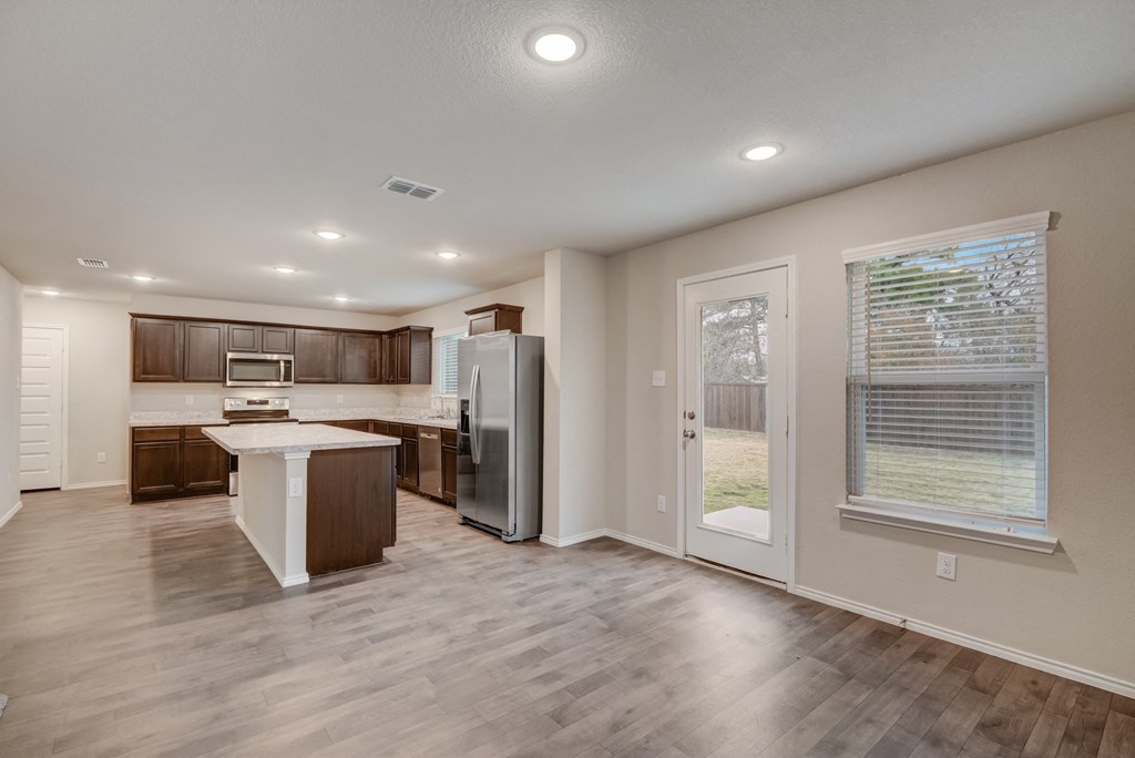 an open kitchen and living room with a door to a backyard