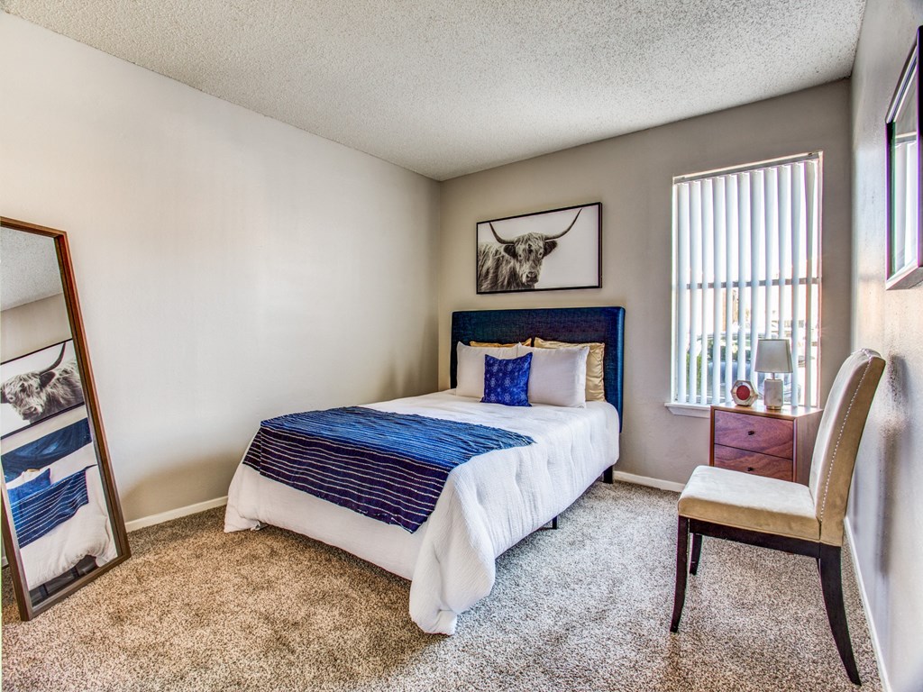 Three-Bedroom Apartments in Fort Worth, TX- Monarch Pass- Bedroom with Large Bed, Wall-to-Wall Carpeting, and White Walls